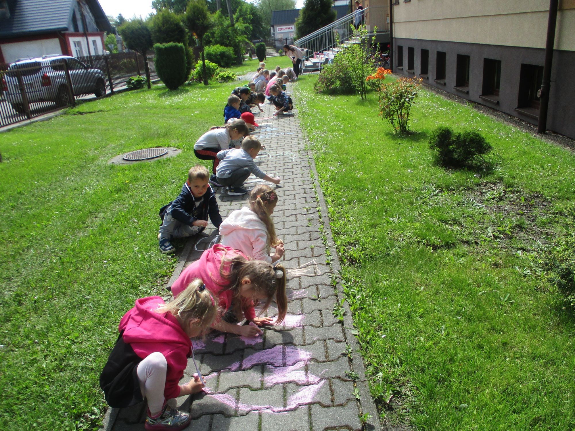 Malowanie kredą po chodniku przez przedszkolaki